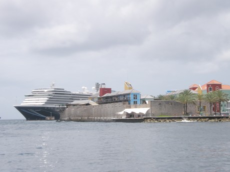 Modern cruise ship docked by centuries old fort