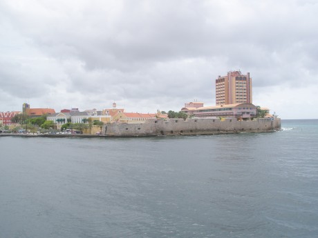 Ancient Curacao fort in shadow of Caribbean style skyscraper